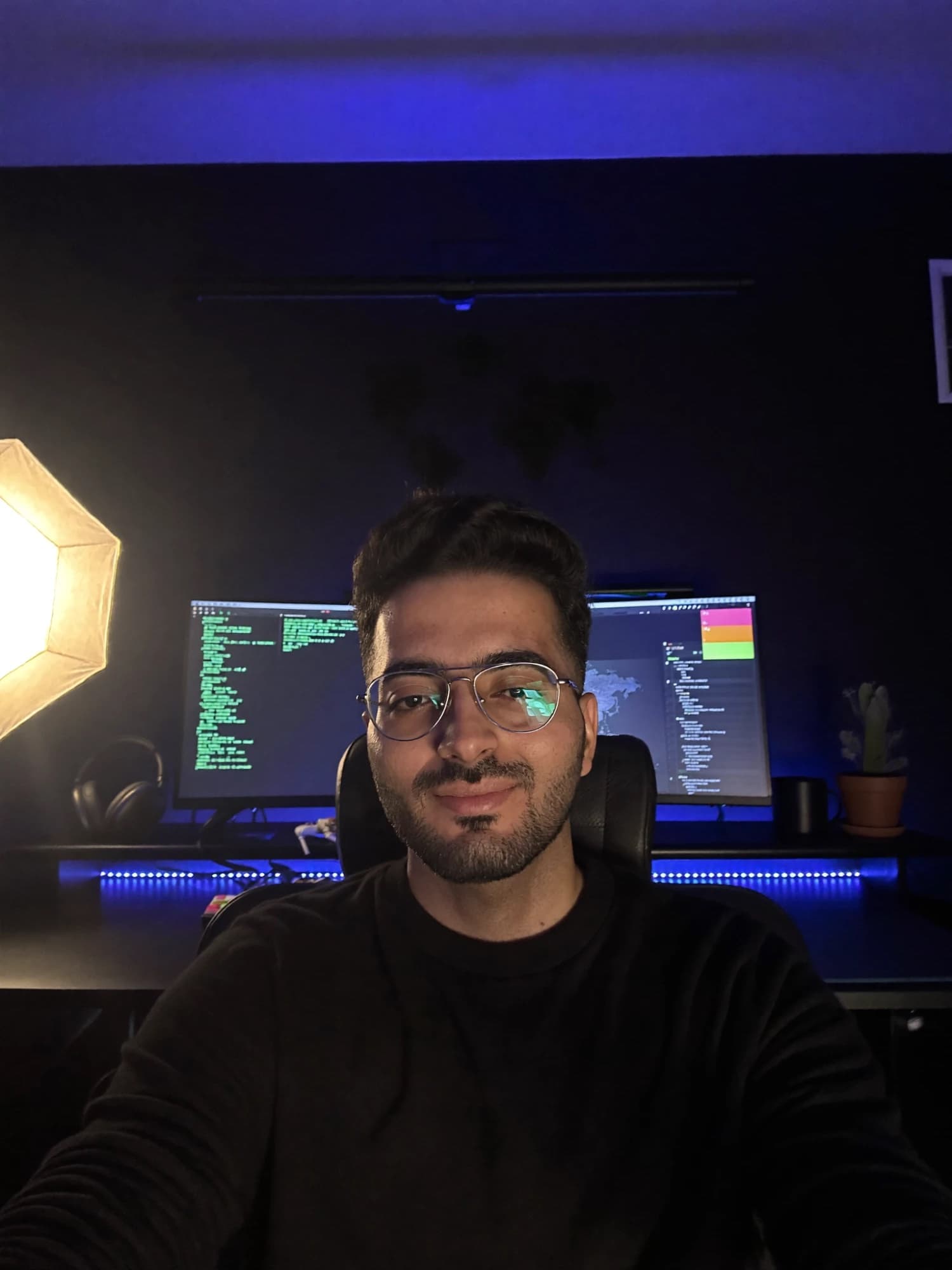 Shahzaib Shoaib at his desk, with code on the monitors behind him